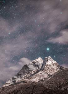 Night photo of a big mountain peak with starts behind it.