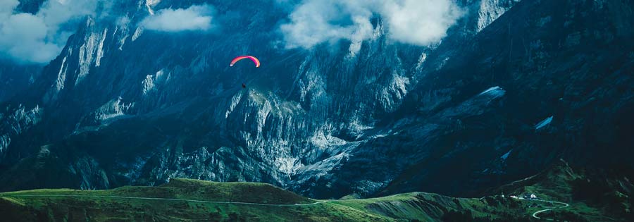 Person paragliding  against big mountains.