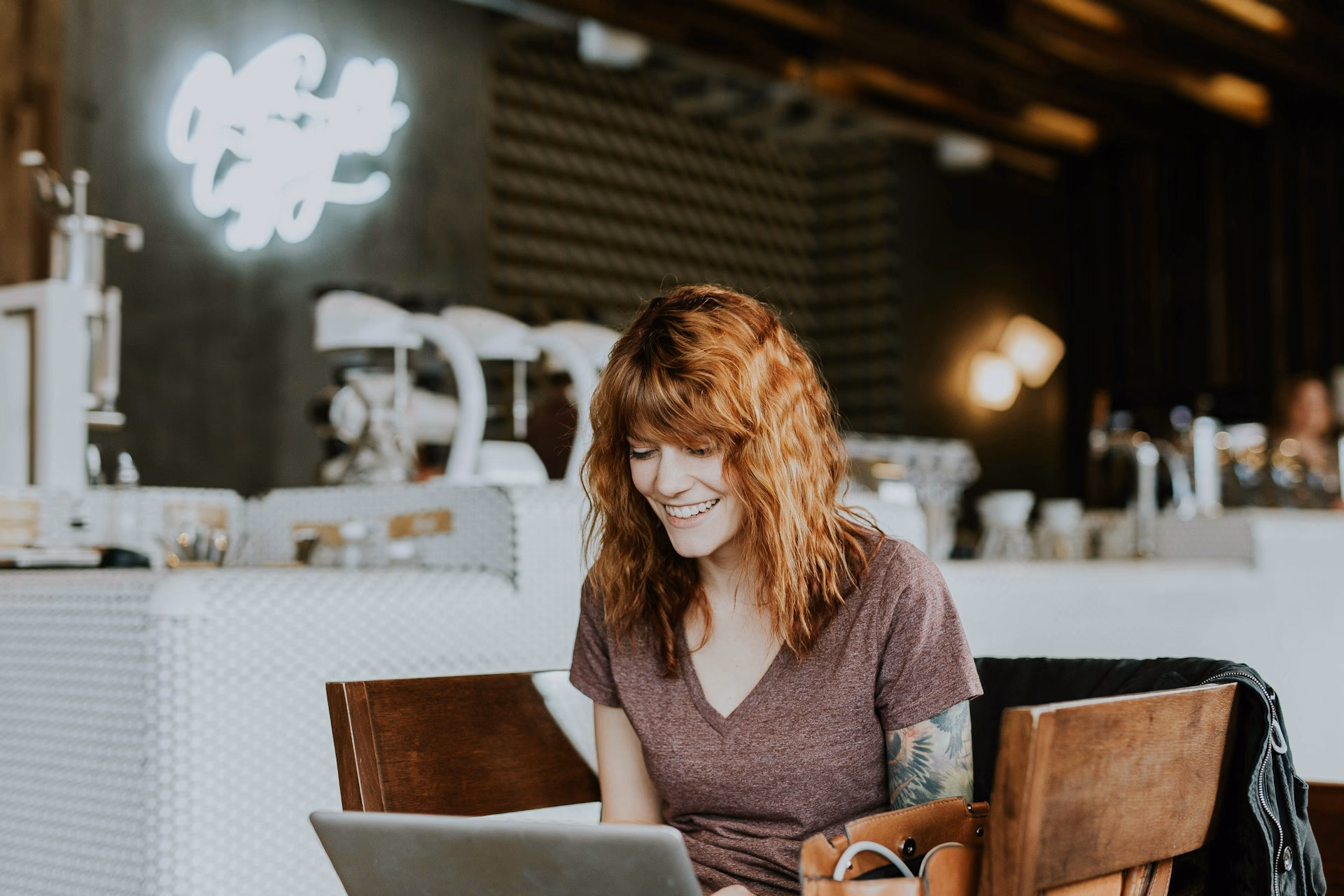 Red haired lady smiling at her computer screen in a modern workspace