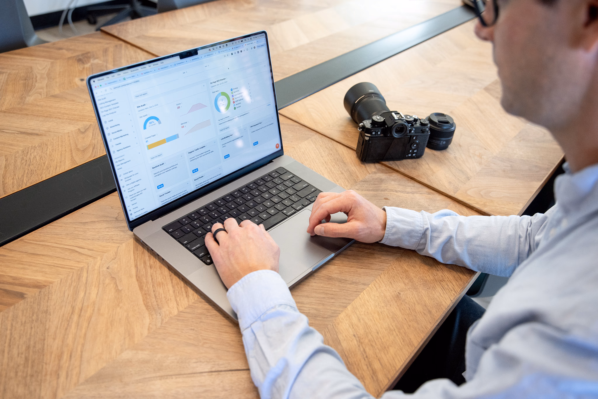 Photographer checking his SEO rankings on a macbook laptop with a camera on the desk